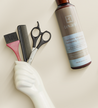 Shampoo bottle, brush, comb, and scissors on a beige background