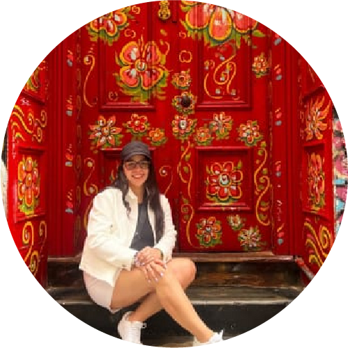 Woman sitting in front of a red decorated wall with floral patterns