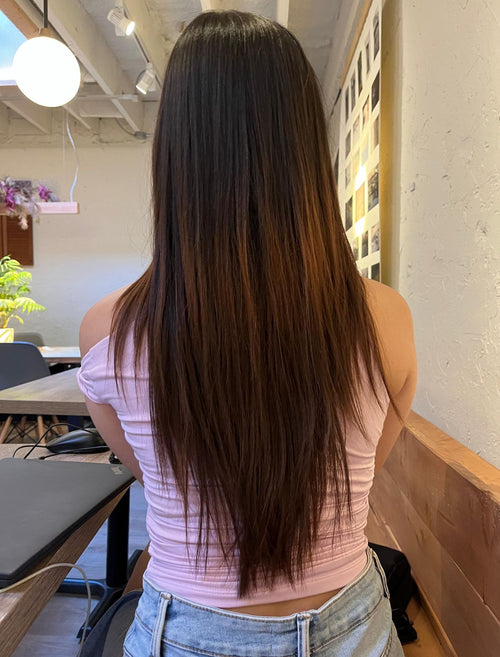 Person with long, straight hair standing indoors in a casual setting.