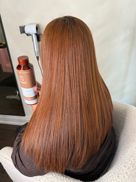 Client with long copper hair holding the Chocolate keratin treatment in a salon