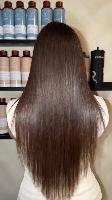 Long glossy brown hair after a keratin treatment, product shelf behind